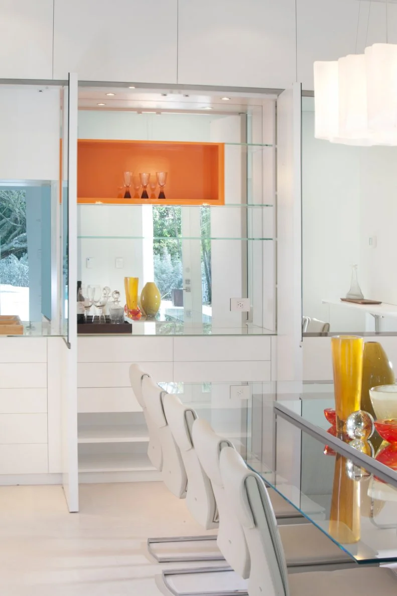 Modern dining room with a glass table and mirrored, hidden bar
