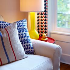Living Room Features Blue and Red Accent Pillows and Yellow Lamp