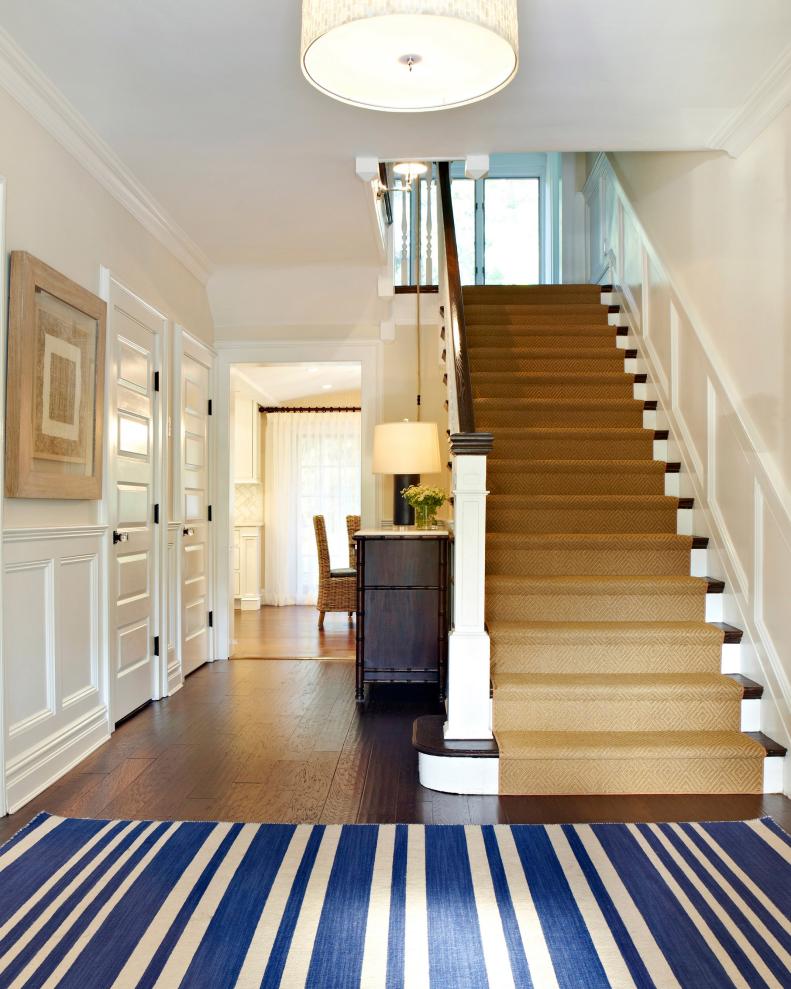 Entryway With Wood Stairs, Brown Carpet Runner and Striped Area Rug