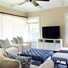 Neutral Den With Blue Tufted Ottoman and Ivory Chairs