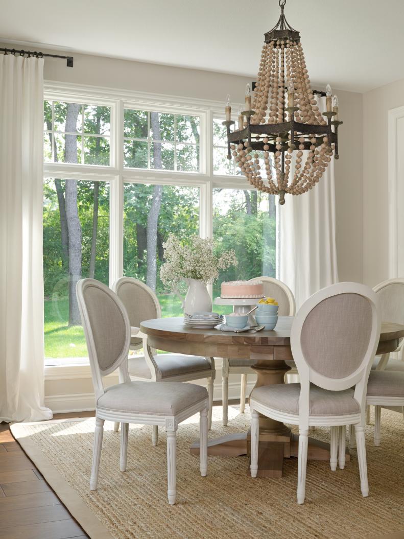 Dining Room With White Curtains, Neutral Chandelier and White Chairs 