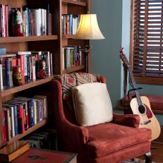 Blue Library With Red Armchair and Wooden Blinds