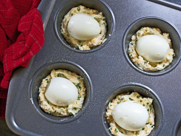 Place boiled eggs on uncooked batter to make an easy cheddar chive muffin breakfast for overnight holiday guests.