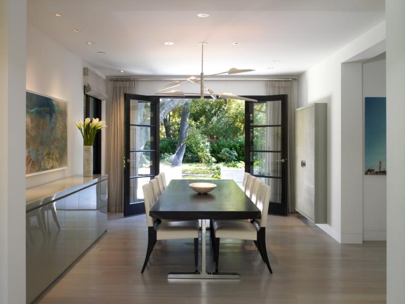 Modern White Dining Room With Dark Dining Table and Open French Doors