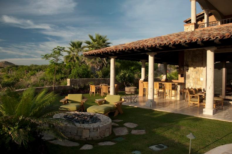 Mediterranean Home Exterior With Stone Patio, Grassy Area & Fire Pit