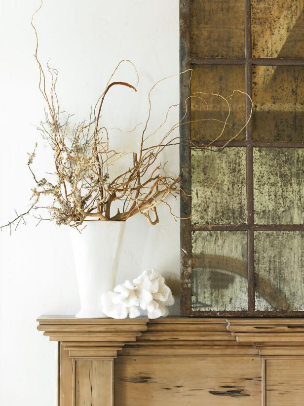 Wood Mantel Topped With Rustic Paneled Mirror and Vase of Branches