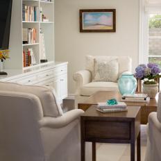 Family Room in Shades of Cream With Upholstered Armchairs and Built-In Cabinetry