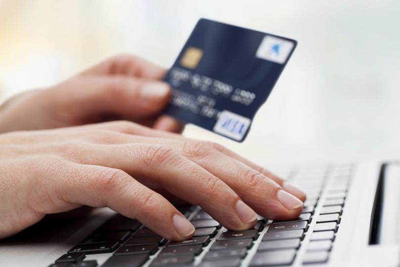 woman typing in debit card number on computer