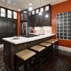 Bold Orange Kitchen Features Dark Wood Cabinetry and Dark Wood Flooring