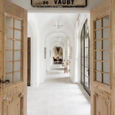 Wooden French Doors Open to Airy White Hallway