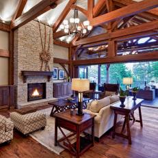 Inviting Traditional Living Room With Intricate Ceiling Beams and Tall Stone Fireplace 