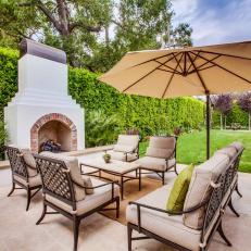 Spanish Style Outdoor Fireplace With Cushioned Seating and Umbrella Cover 