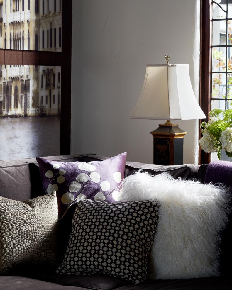 Four Throw Pillows in Corner of Gray Sofa With Lamp Behind