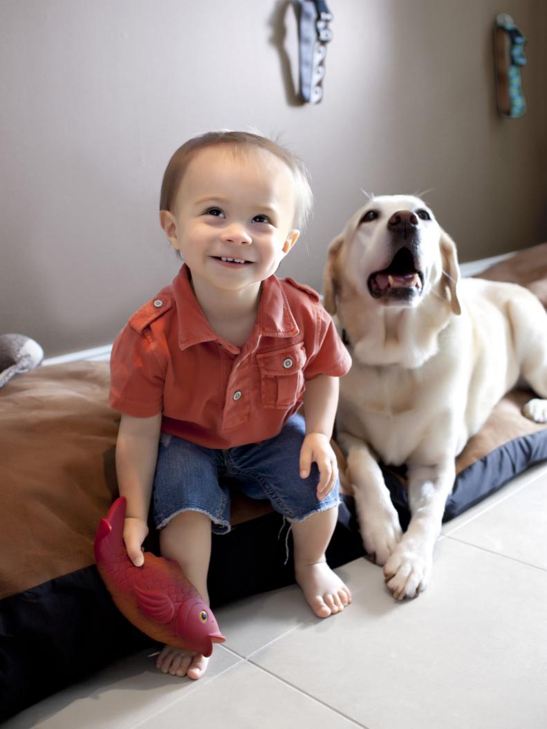 Little boy and dog sitting on a dog bed.