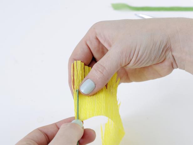 Cut slits into the top 1 1/2 inches of the folded crepe paper to create fringe, and hold the end of floral wire up to the edge of the fringe.