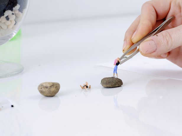 Pick out a flat rock for your figures to stand on — look for small rocks in your yard. Dip the feet of your first figure in waterproof glue, and attach to the flat rock.