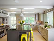 Neutral Kitchen With Gray Island, White Cabinets and Yellow Stools