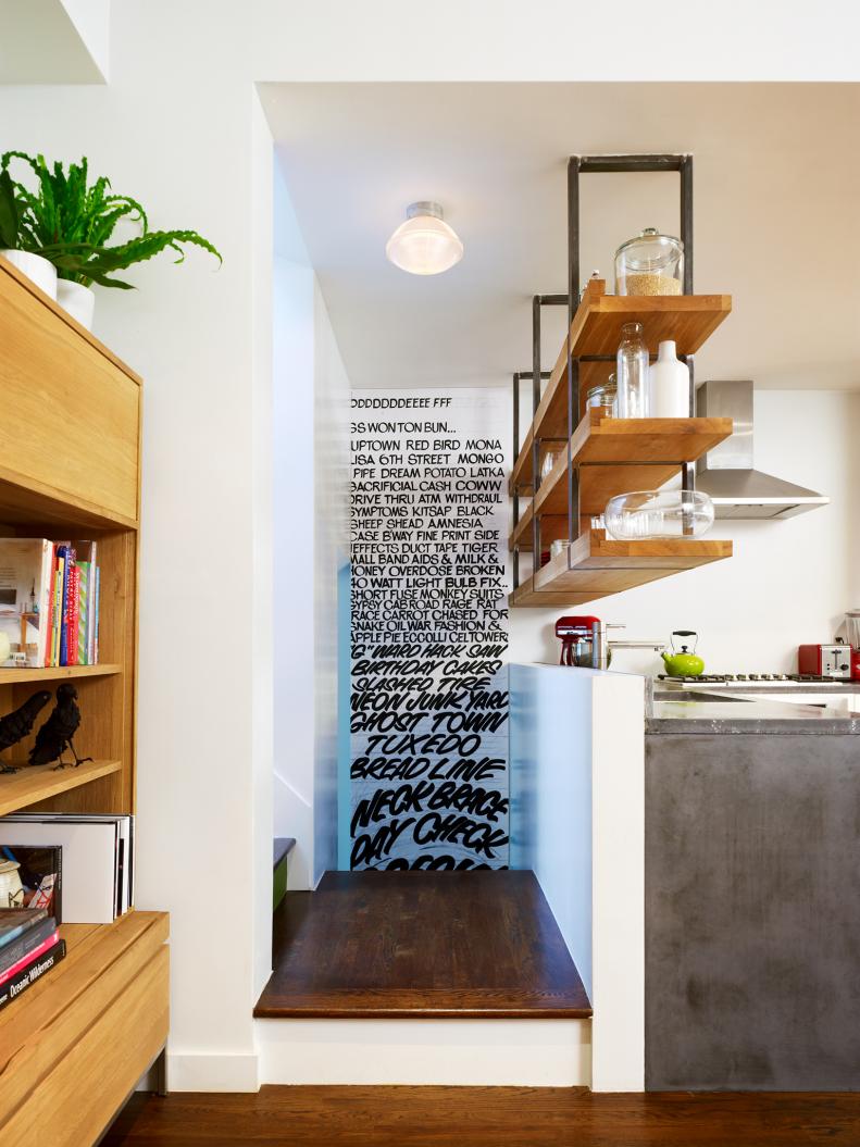 White and gray kitchen, with open upper shelving and graffiti art. 