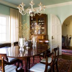 Transitional Dining Room With Arched Door and Glass Chandelier