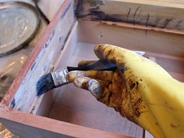 If the felt was held in place with glue, stripping is necessary to create a clean surface before restaining the wood. First, don chemical-resistant gloves, then pour stripper into a metal pan and use a disposable chip brush to apply a thick coat of the chemical to the glue-covered areas.