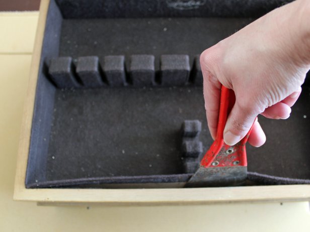 Using a metal paint scraper, pry the felt liner away from the sides of the old cutlery box.
