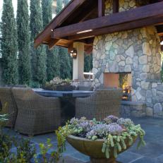 Outdoor Dining Area With Stone Fireplace and Wicker Seating