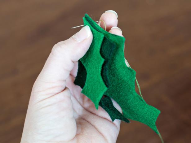 Pinch together 2-3 holly leaves of varying colors and shapes. Use green thread on an all-purpose sewing needle to secure leaves together at the top for the cat toy.