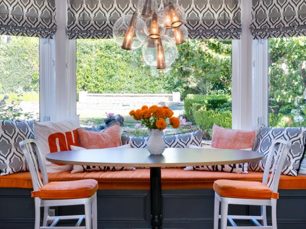 Kitchen Banquette with Orange Cushions and Graphic Roman Shades