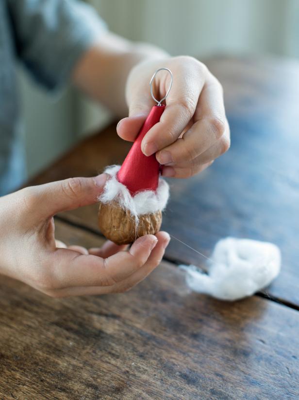 Separate and glue a piece of cotton ball to the bottom of the red hat, creating a miniature Santa hat.