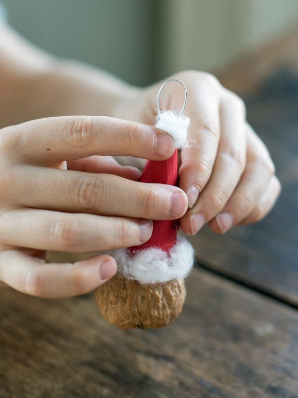 Attach a small piece of cotton ball to the top of the hat and allow all glue to dry to create the ornament's festive Santa hat.