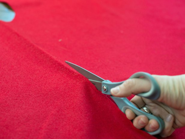 When the felt for the tree skirt base is unfolded, it should be a circle with a hole in the middle. Use scissors to cut a straight slit from the skirt edge to the center hole, so the skirt can be easily slid around the tree trunk.