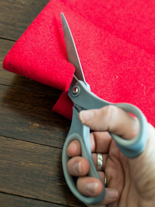 To create the pattern for a Christmas tree skirt, cut along the previously made pencil line, then cut the corner where the folds meet in a quarter circle pattern to create a hole for the tree trunk.