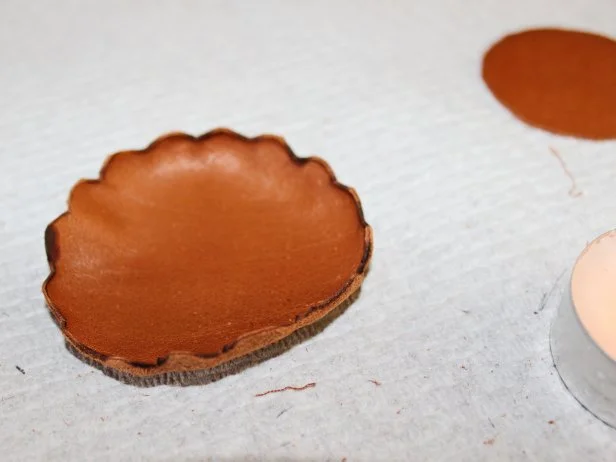 Continue rotating the leather cutout, heating a small area at a time to curl it until the edges have all drawn in. Repeat the curling process for the second leather circle.