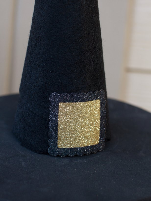 As a finishing touch, create a buckle by placing a small square of gold glitter paper behind a small picture frame sticker, securing them both to the hat with hot glue.