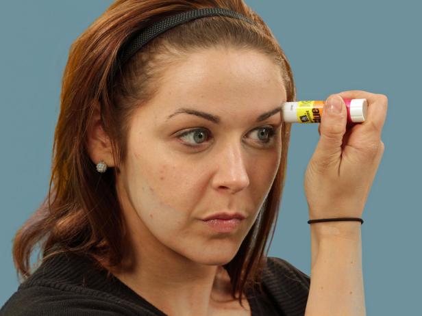 Flatten the eyebrows by rubbing a glue stick over the outside edge of the eyebrows in the direction of hair growth.