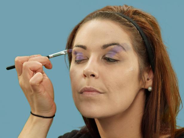 Use a medium makeup brush to apply purple metallic cream makeup over the eyes and over the outer edges of the brow.