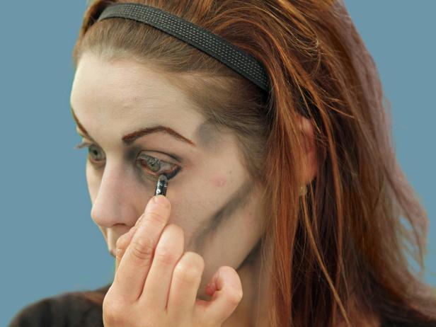 To create the eyes of the undead, line the eyes using black eyeliner on the top and bottom in a heavy, uneven pattern.