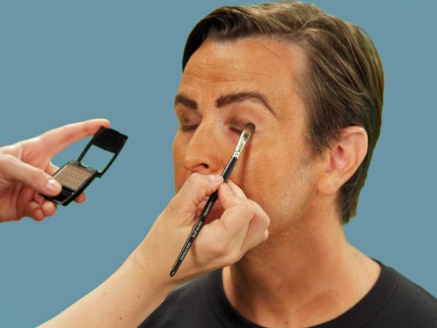 Using an eye shadow brush, apply brown eye shadow to the crease of the eyes, blending it down to the lower lid.