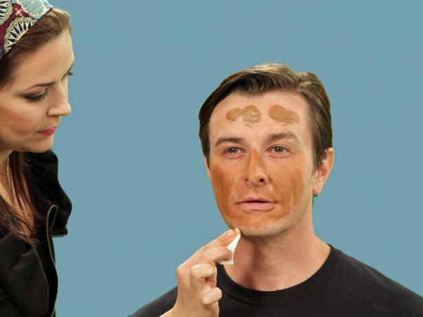 Woman applying Halloween pirate makeup to man