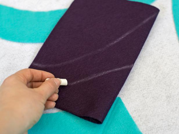 Determine placement for complimentary colors and shapes of felt for tree skirt. Cut piece of felt a little large than desired design, fold in half then chalk half design onto felt and cut to create a symmetrical shape.