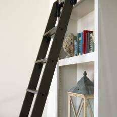 Black Library Ladder Against White Shelves