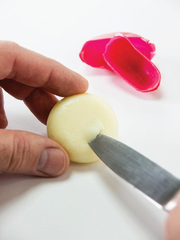 Remove the wax casing from the cheeses. Use a paring knife to carefully cut a divot in the center of the cheese that's approximately the size of a green olive slice.