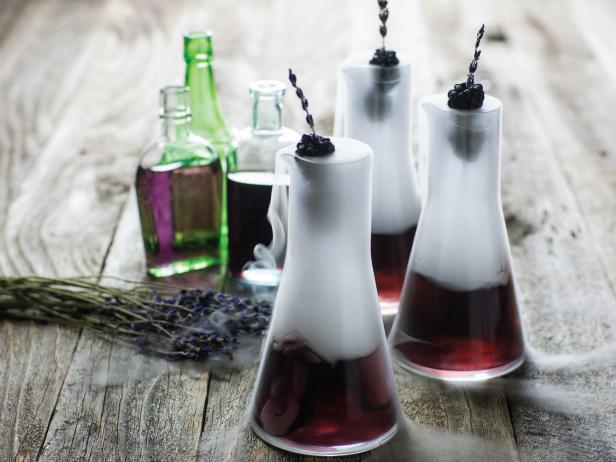 Purple Cocktails in Beakers With Raspberry Skewers