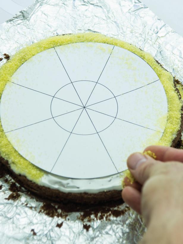 Print out the candy corn brownie template and cut out the outer circle and set it aside. Place the two inner circles (still connected) in the center of the brownie and sprinkle yellow sugars over the icing. Tip: Press it slightly with dry fingertips to adhere if necessary (Image 2).