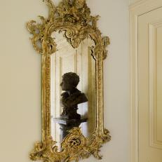 Ornate Gold Mirror Reflects Artwork in Hallway