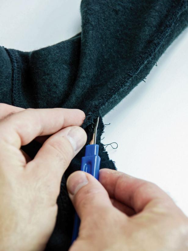 With a seam remover, carefully remove the hoodie seam along the side and inside of the arm starting at the waistband and working toward the cuff.