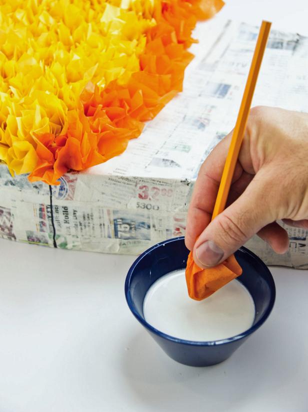 Hold the tissue paper to the pencil and dip the end in school glue.