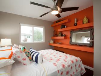 Bedroom With Colorful Bedding, Orange Storage Wall and Framed Mirror