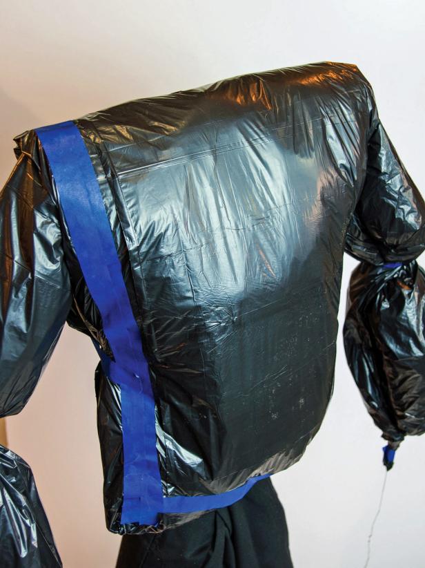 Repeat for the other side. Open up a black trash bag and fold it in half lengthwise. Stuff the half bag for the body about 4 inches tall and tape it closed on the top and bottom. Fold the bag over the top of the 6” pipes and T. On the front, the bag should reach the top of the pants. On the back, it may only come about half way down.