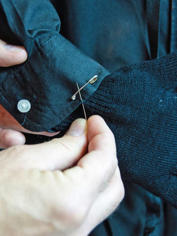 Insert the wire into the glove ending in the middle finger. Button the cuff around the glove and sew the two together all the way around the cuff with needle and black thread.
